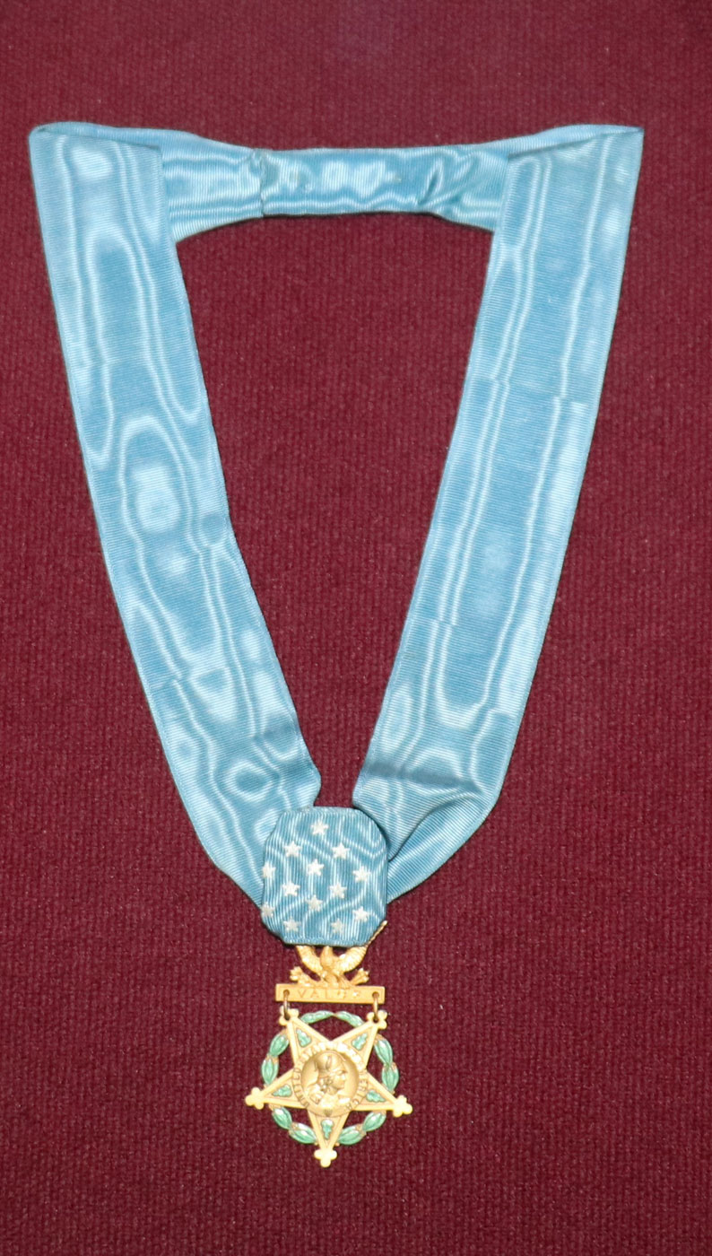 A medal with a light blue ribbon on display at the West Point Museum.